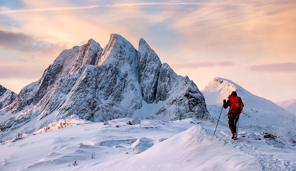 Mountaineer man climbs on top snowy mountain with colorful sky in morning